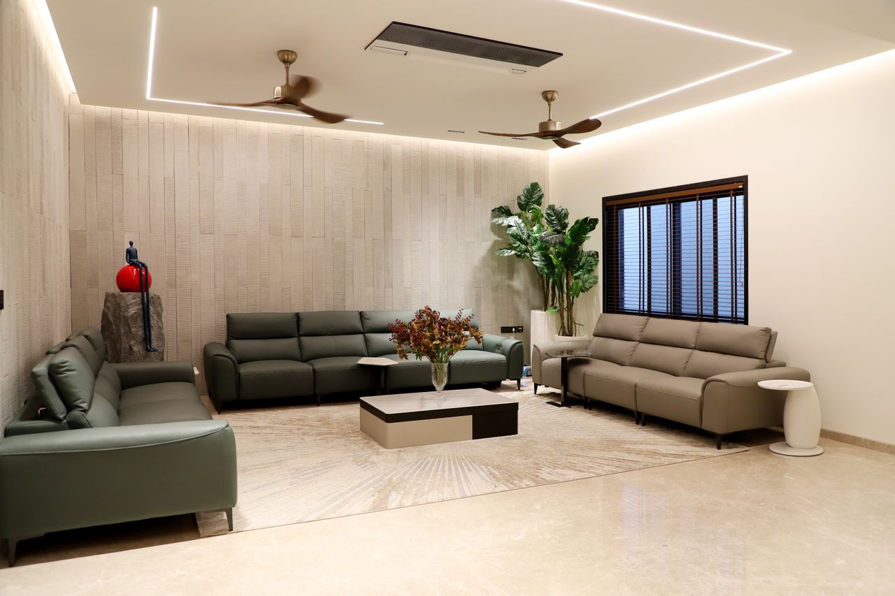 about-us Spacious modern living room featuring green sofas, indoor plants, and minimalistic decor.